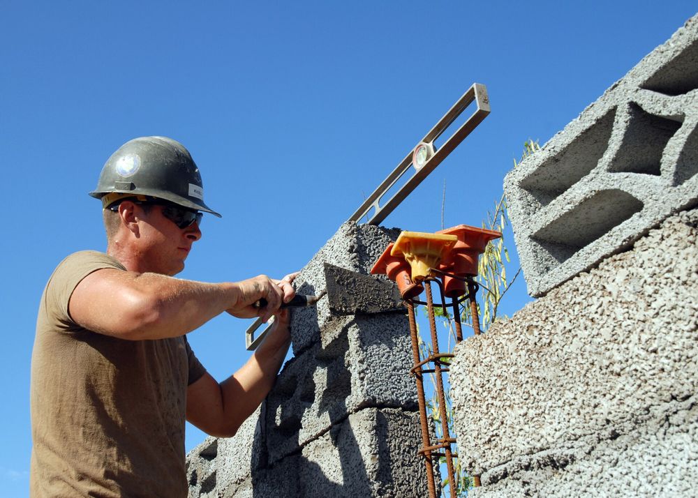 A builder laying a concrete block wall